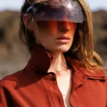 Personne portant lunettes de soleil futuristes, chemise marron.